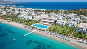 Widok na morze Egejskie z hotelowymi leżakami i niebieskim basenem na greckim kurorcie all-inclusive